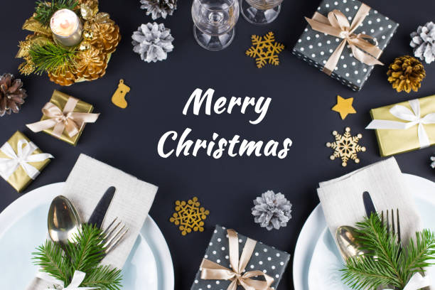 istock Merry Christmas greeting card with table setting with plates, silverware, gift box and decorations in black and gold 1060447652
