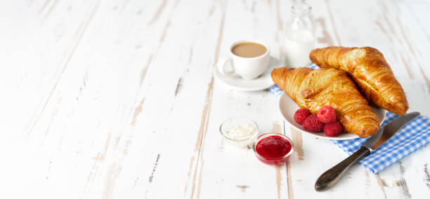 два круассана и кофе на завтрак на белом столе - croissant morning white breakfast стоковые фото и изображения