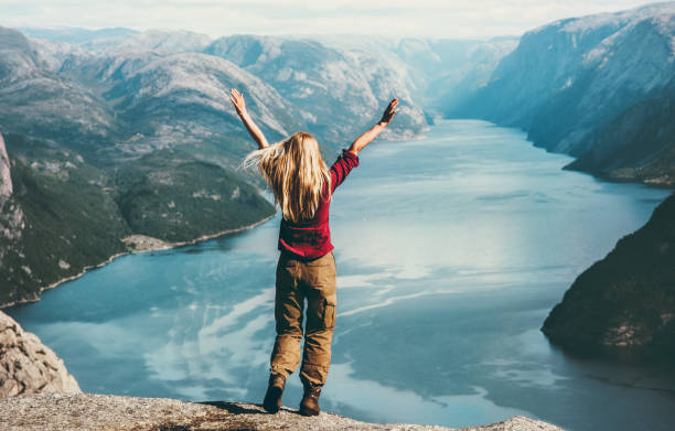 blonde woman traveling in norway emotional raised hands above lysefjord adventure lifestyle wanderlust concept vacations outdoor success and wellness - common women teenage girls exercising imagens e fotografias de stock