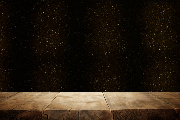 istock rustic wooden table in front of glitter black and gold bright bokeh lights. 1060474662