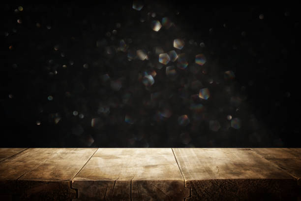 istock rustic wooden table in front of glitter black and silver bright bokeh lights. 1060474754