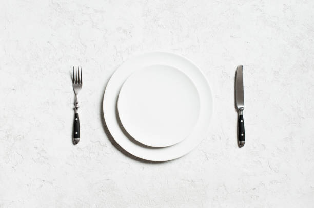 istock White plate and cutlery on the white textured table 1060476854