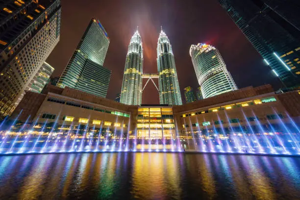 Ultra wide angle Nightshot of Kuala Lumpur Petronas Towers from below with colorful illuminated fountain in downtown Kuala Lumpur. Petronas Twin Towers, Kuala Lumpur, Malaysia, Asia
