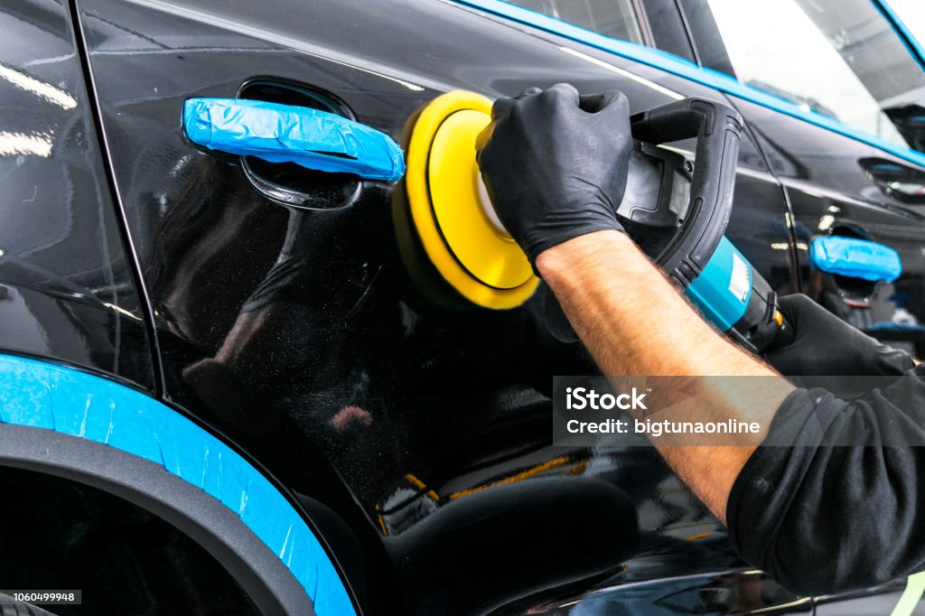 Travailleur de cire polish voiture mains ruban protecteur s’appliquant avant polissage. Meulage et polissage de voiture. Détailler de la voiture. L’homme tient un polissoir dans la main et polit la voiture - Photo de Voiture libre de droits