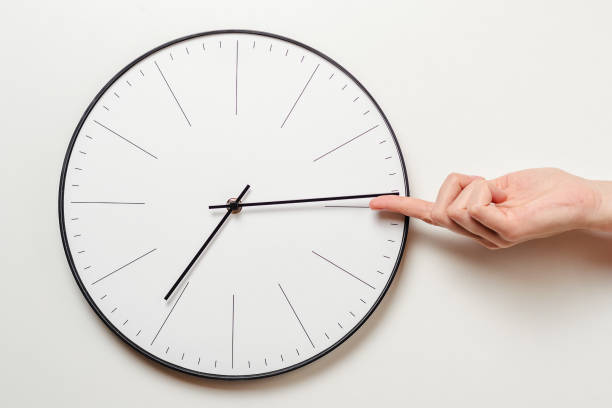 Woman hand stop time on round clock, female finger takes the minute arrow of the clock back, time management and deadline concept Woman hand stop time on round clock, female finger takes minute arrow of the clock back, time management and deadline concept bending over backwards stock pictures, royalty-free photos & images