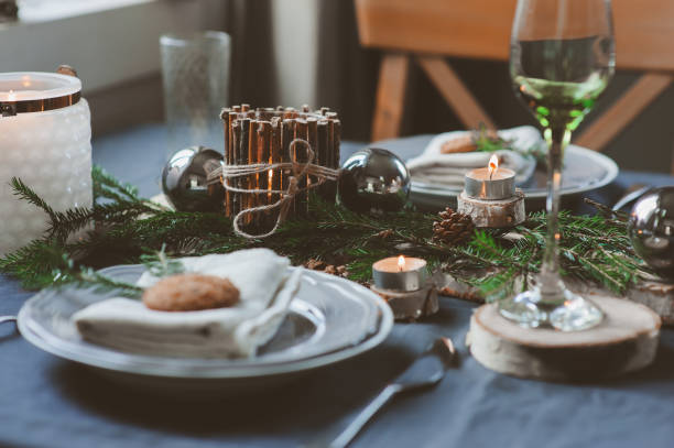 istock Festive Christmas and New Year table setting in scandinavian style with rustic handmade details in natural and white tones. Dining place decorated with pine cones, branches and candles 1060512490