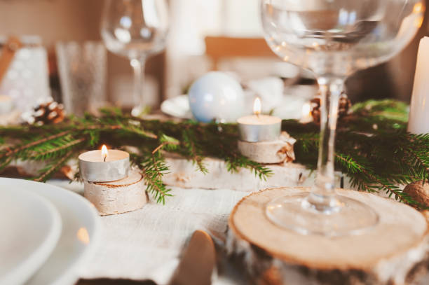 istock Festive Christmas and New Year table setting in scandinavian style with rustic handmade details in natural and white tones. Dining place decorated with pine cones, branches and candles 1060512526