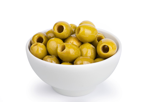 Green olives in a white ceramic bowl isolated on white background.