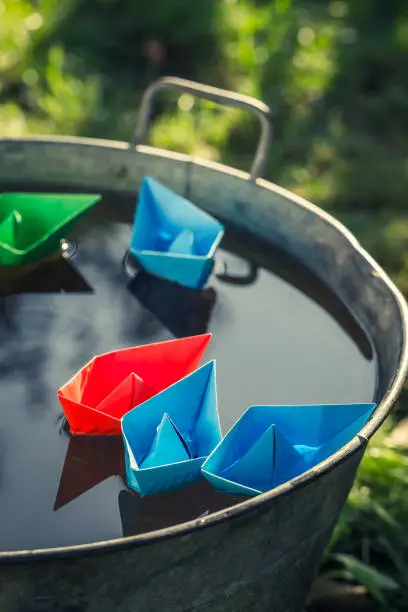 Photo of Origami paper boats quietly floating on water in garden