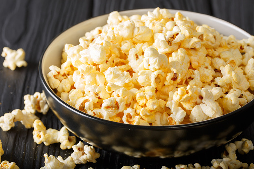 Stock photo showing close-up, elevated view of round tin of Belgian, dark chocolate covered popcorn.