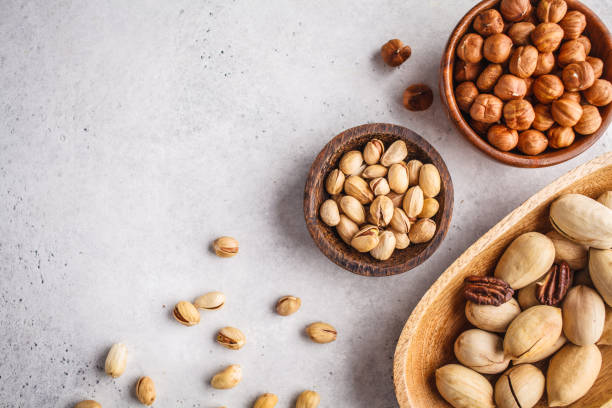 istock Hazelnuts, pistachio and pecans in wooden bowls on white background. 1060536088