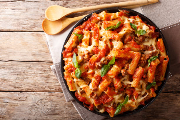 Pasta ziti with bolognese sauce and cheese close-up. horizontal top view, rustic style Pasta ziti with bolognese sauce and cheese close-up on the table. horizontal top view from above, rustic style tomato photos stock pictures, royalty-free photos & images