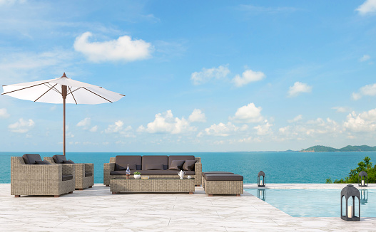 Outdoor pool terrace living area 3d render,There are white marble floor.Furnished with rattan furniture.There have bright sunlight and beautiful sea view.