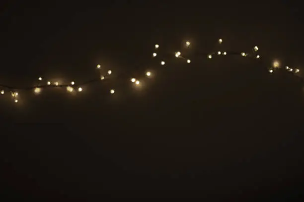 Photo of Abstract Christmas lights on  black  background. Defocused  Glowing light bulb garland, copyspace