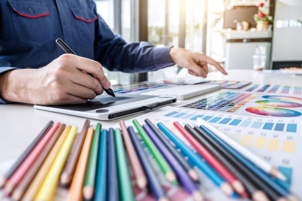 istock Image of male creative graphic designer working on color selection and drawing on graphics tablet at workplace with work tools and accessories 1060554916