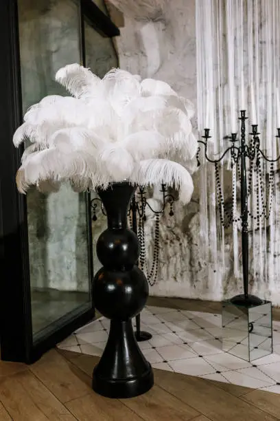 White ostrich feather in black vase, wedding decoration details.