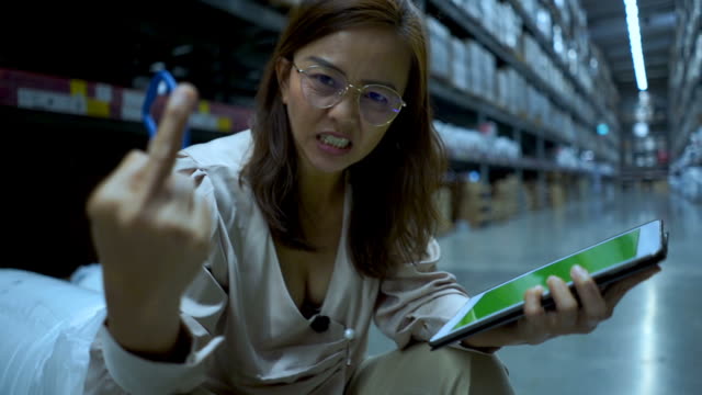 business woman in store  checking inventory on digital tablet , serious emotion ,Showing Middle Finger