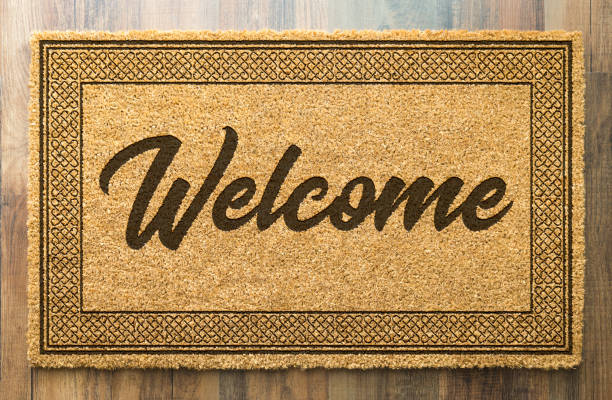 tapete de boas vindas em um fundo do assoalho de madeira - welcome sign doormat greeting floor mat - fotografias e filmes do acervo