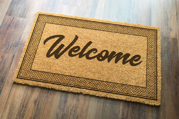 tappetino di benvenuto su sfondo pavimento in legno - welcome sign doormat greeting floor mat foto e immagini stock