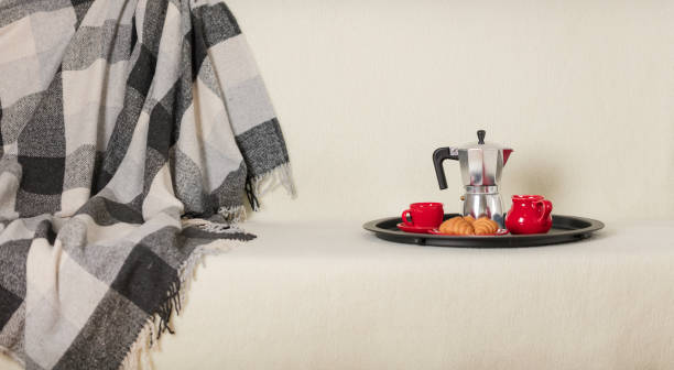 istock Round black metal tray with a coffee maker and a cup on a white sofa with a gray plaid and pillows. 1060562972
