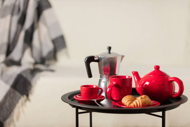 istock Round black metal coffee table with a coffee maker and a kettle for tea against the background of a white sofa with a gray blanket. 1060563028