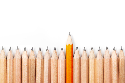 Orange pencil standing out from crowd of black pencils on white background.Concept of leader,unique,different