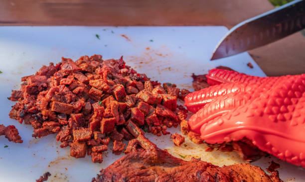 posiekany grillowany stek na białej desce do krojenia z ręką w czerwonej gumie na rękawicy i nożu - zbliżenie & selektywne skupienie - steak close up grilled skirt steak zdjęcia i obrazy z banku zdjęć