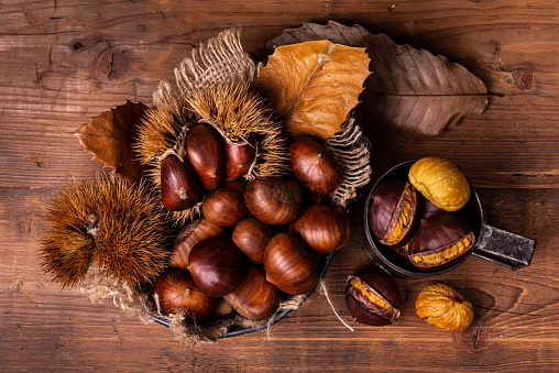on the rustic wooden table a pile of fresh and roasted chestnuts