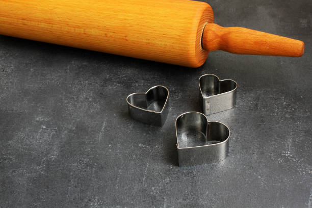 Heart cookie cutter and rolling pin on dark board