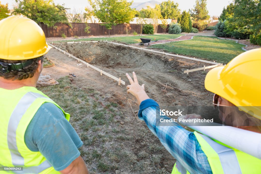 Male and Female Workers Overlooking Pool Construction Site Swimming Pool Stock Photo