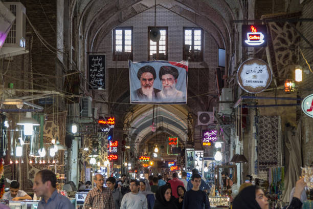 street of the isfahan bazarw ith the portraits of the 2 supreme leaders of the islamic republic of iran, ali khamenei & ruhollah khomeini hung on the roof - covered bazaar imagens e fotografias de stock