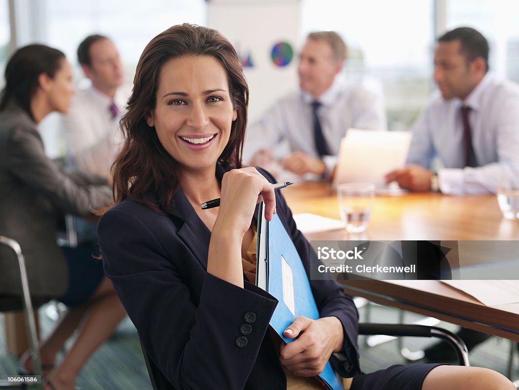 Portrait d'un souriant executive tenant des fichiers avec des collègues di - Photo de Salle de réunion libre de droits