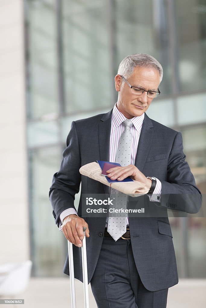 Uomo d'affari di successo guardando orologio in aeroporto - Foto stock royalty-free di 60-64 anni