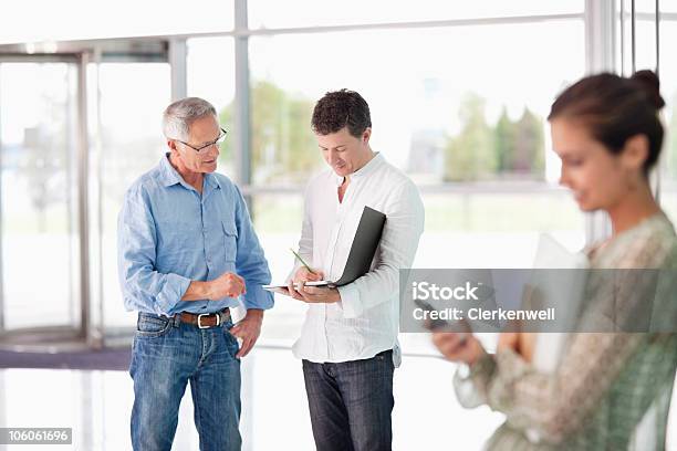 Dos Hombres Sobre El Informe En Primer Plano Mientras Que Mujer Foto de stock y más banco de imágenes de 25-29 años