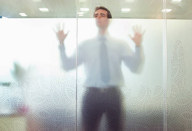 ejecutivo de negocios de pie por detrás de puerta de vidrio - mirando através fotografías e imágenes de stock