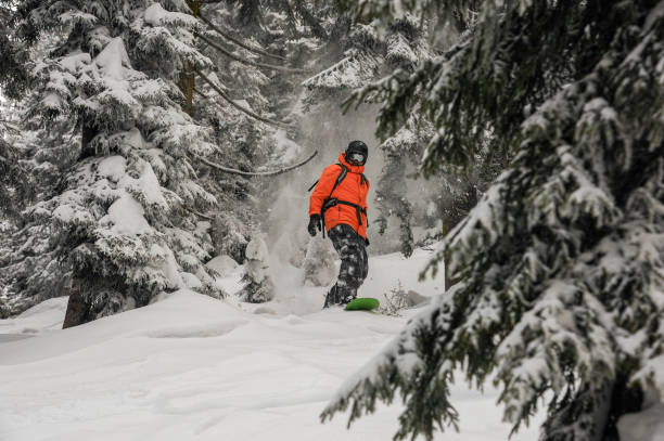 istock Man riding down the hill on the green snowboard between trees 1060619678