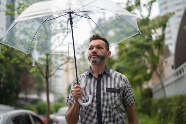 istock Mature businessman walking on a raining day with umbrella 1060622112
