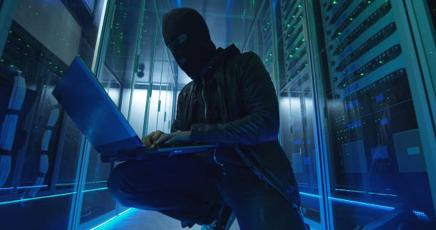 Anonymous hacker breaking into server system Hacker in black mask using computer and breaking servers of data center stealing information white mask on computer for internet security concept stock pictures, royalty-free photos & images