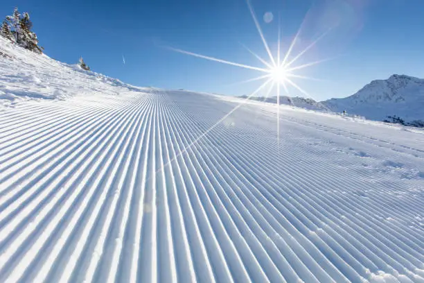 Fresh snow on ski slope during sunny day, Alps mountains.