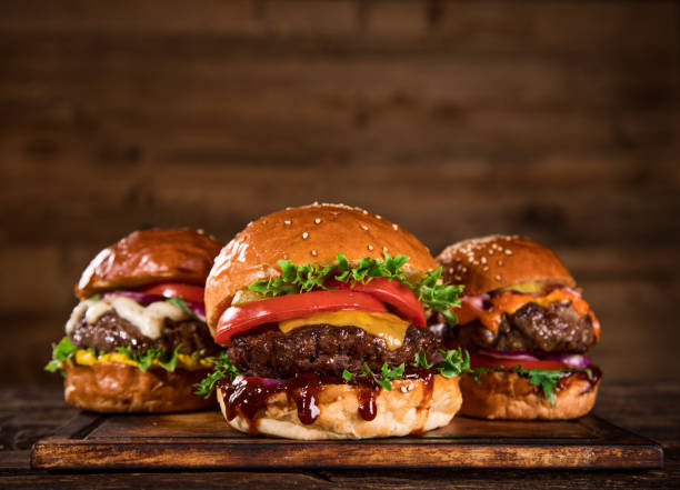 istock Tasty burgers on wooden table. 1060628444