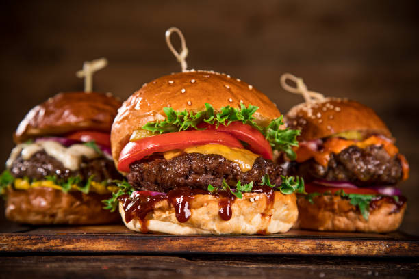 istock Tasty burgers on wooden table. 1060628678