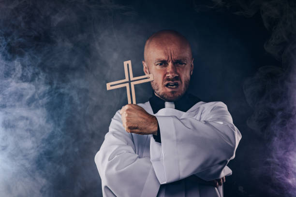 Catholic priest exorcist in white surplice and black shirt Catholic priest exorcist in white surplice and black shirt with cleric collar praying with crucifix exorcism stock pictures, royalty-free photos & images