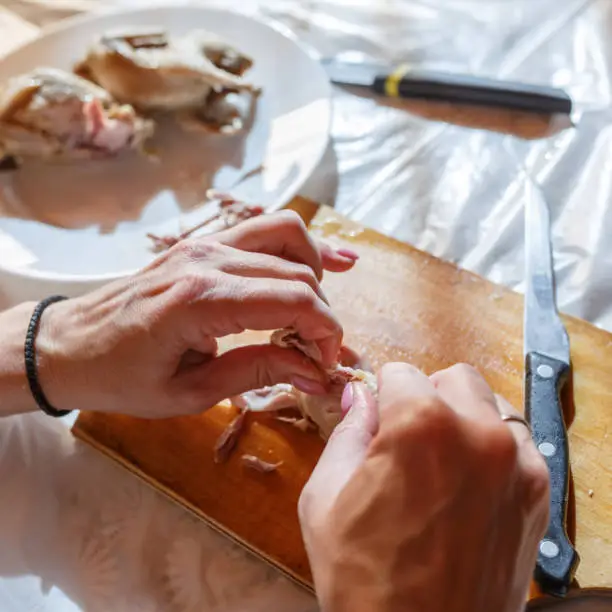 Photo of Woman by hands is disjoining the quail meat in the kitchen