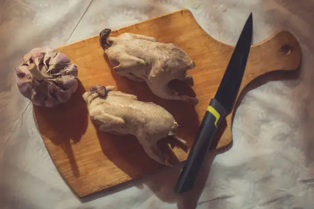 Photo of Pair of cooked quails lie on a wooden cutting board as an example of healthy eating