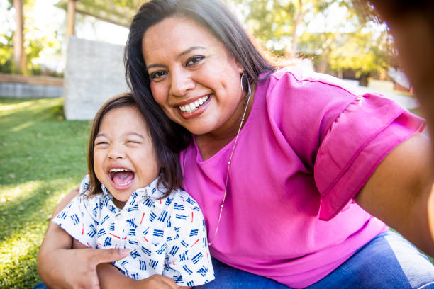 Mom Taking a Selfie with Son A young mexican mother takes a selfie with her down's syndrome son in the park. child care photos stock pictures, royalty-free photos & images