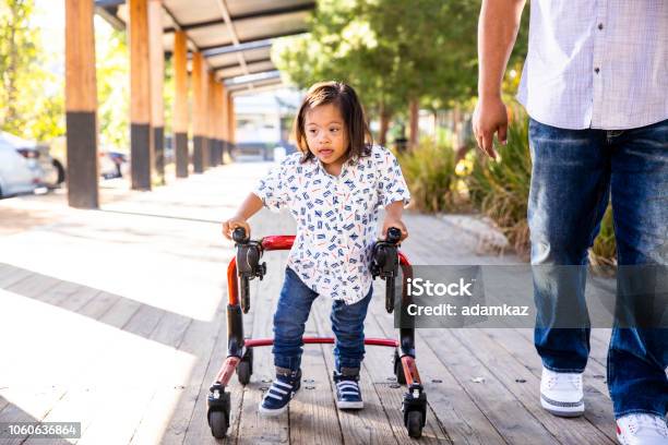 Hispanic Boy With Downs Syndrome Using Walker With Dad Stock Photo - Download Image Now