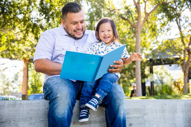 Dad Reading to his Son A mexican dad reads a book to his son.  The young boy has down's syndrome. guru photos stock pictures, royalty-free photos & images