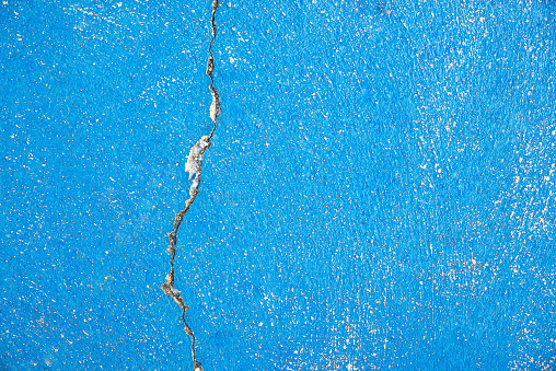 Background of a blue painted cement floor with crack. Closeup from outdoor sports ground.