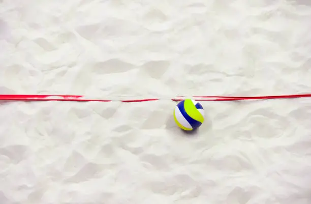 Colorful volleyball ball and red line on top of the sand.