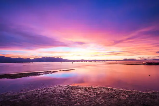 Beautiful sunset on Lake Tahoe with bright purple, pinks and oranges in the sky. Long exposure, calm water